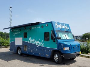 A large blue truck with Bookmobile written along sthe side is parked in front of the ocean