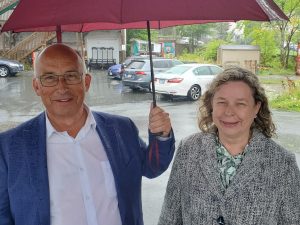 A man and a woman stand under an umbrella in the rain