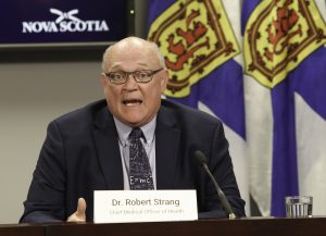 A man sits at a desk and speaks into a microphone