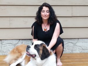 A woman kneels and pats a St. Bernard dog